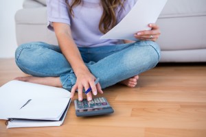 Woman calculating receipts lying on the floor